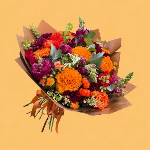 Ramo Ofrenda Magna con cempasúchil naranja, garra de león, perritos morados y calabacitas mini, con envoltura café y listón cobrizo.